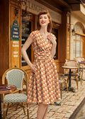 A woman wears a vintage-style cotton dress with an orange and cream checkered pattern and a flared skirt