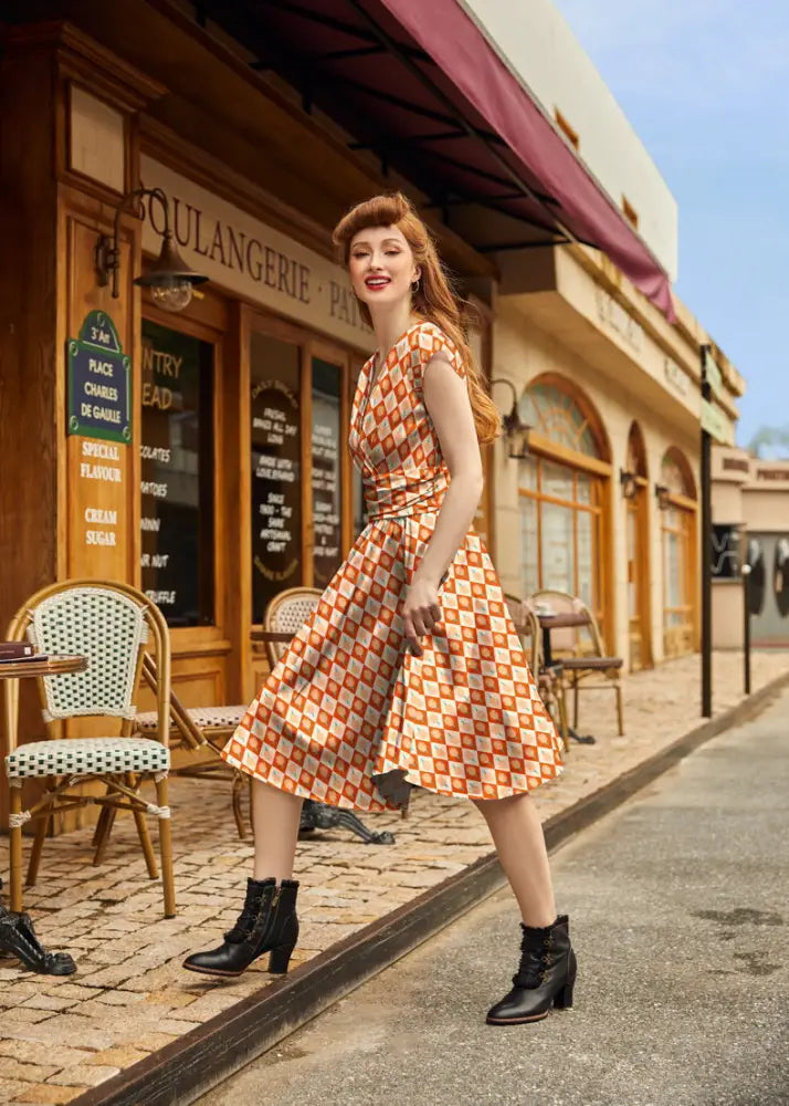 A woman wears a sleeveless cotton dress with an orange and white geometric vintage ice cream print pattern