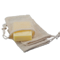 Beige mesh cotton soap saver bag with a yellow bar of soap inside for eco friendly soap storage and exfoliation