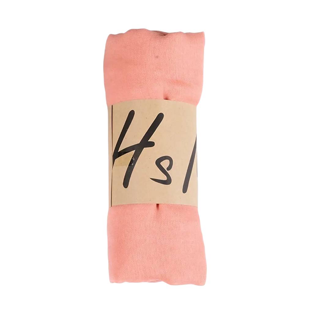 A soft peach-colored cotton winter scarf rolled up and wrapped with a brown paper band for women