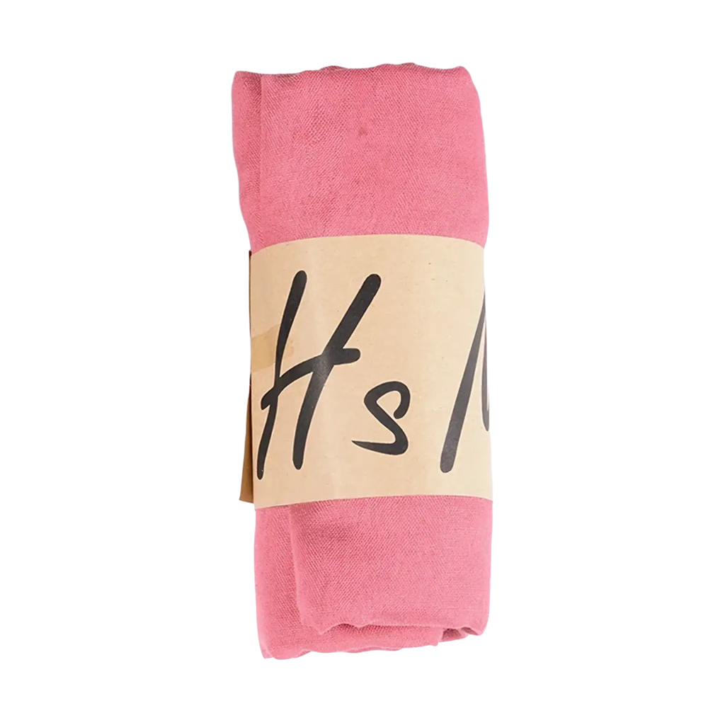 A soft pink cotton winter scarf for women neatly rolled with a beige paper band and black handwritten-style lettering