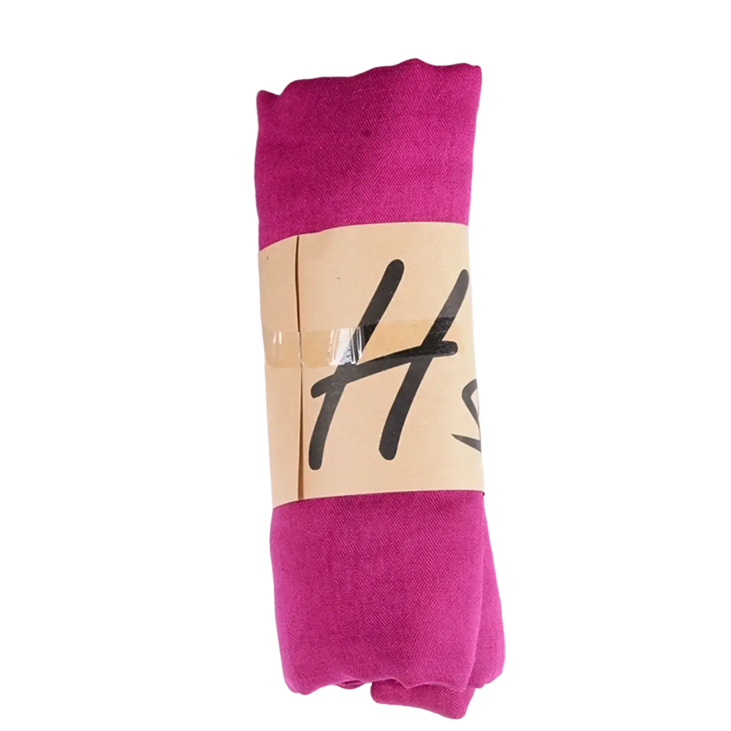 A vibrant magenta cotton winter scarf neatly rolled with a beige label for women solid warm winter use