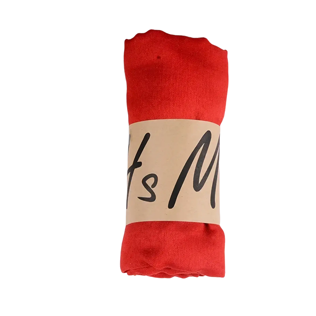 A vibrant red soft cotton winter scarf neatly rolled and secured with a beige paper band for women