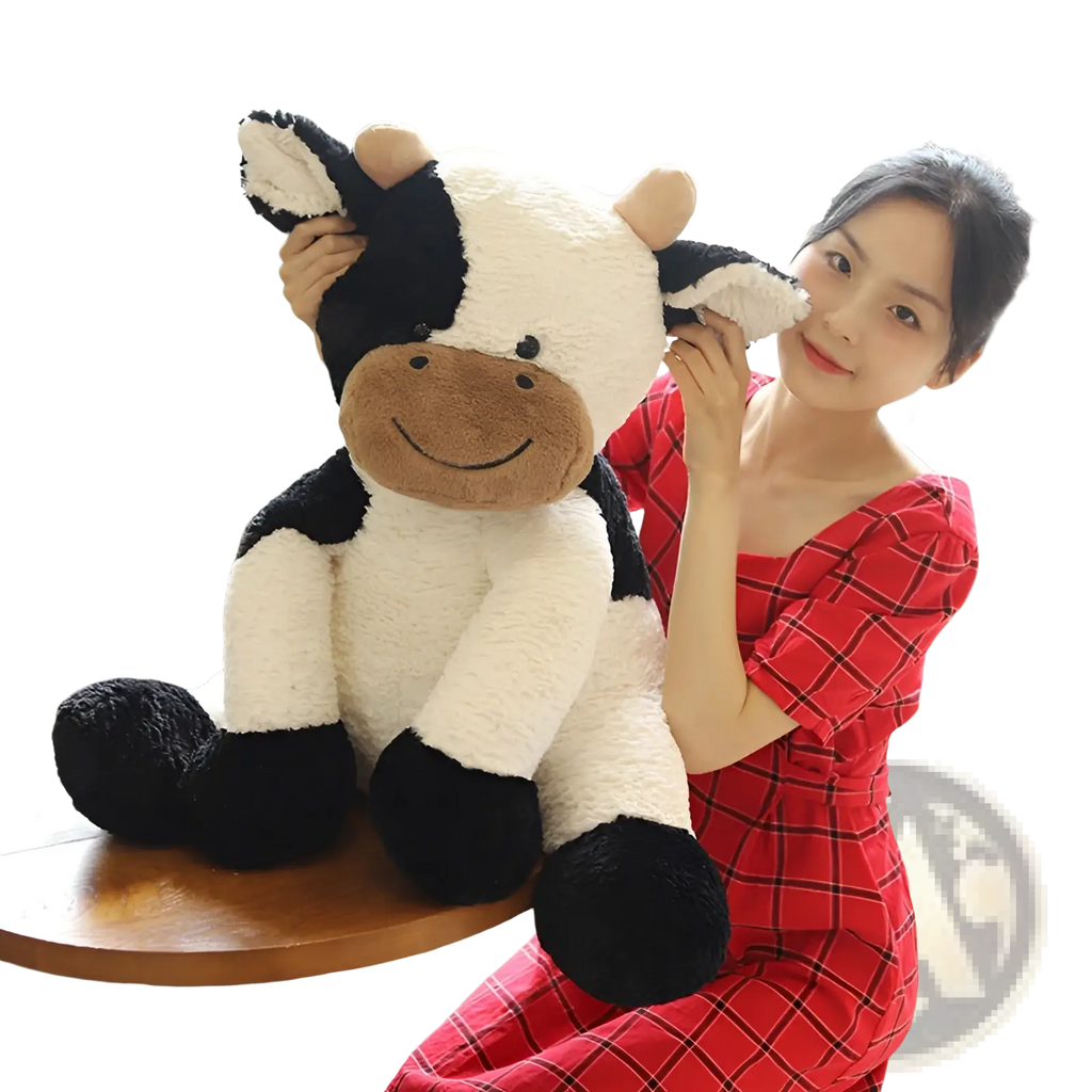 A soft plush cow toy in black and white with a brown smiling face and fluffy texture for cuddling