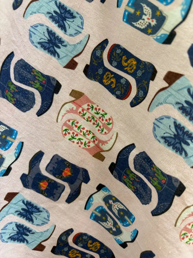 A patterned cotton pleated skirt featuring colorful stylized cowgirl boots print with pockets and retro design