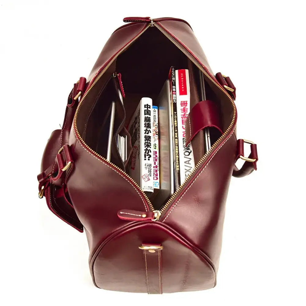 Burgundy crazy horse leather duffel tote bag with gold-toned hardware and zipper closure filled with books