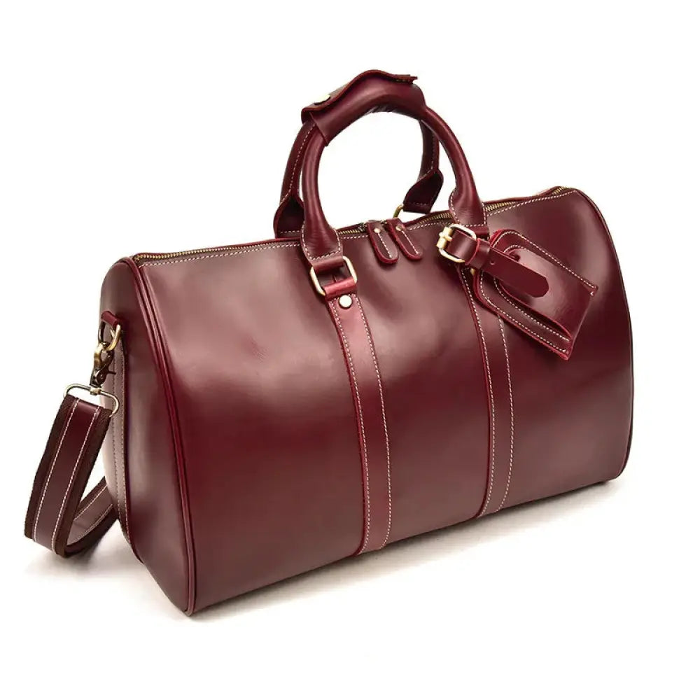 A rich burgundy crazy horse leather duffel tote bag with white stitching, sturdy handles, and a detachable shoulder strap