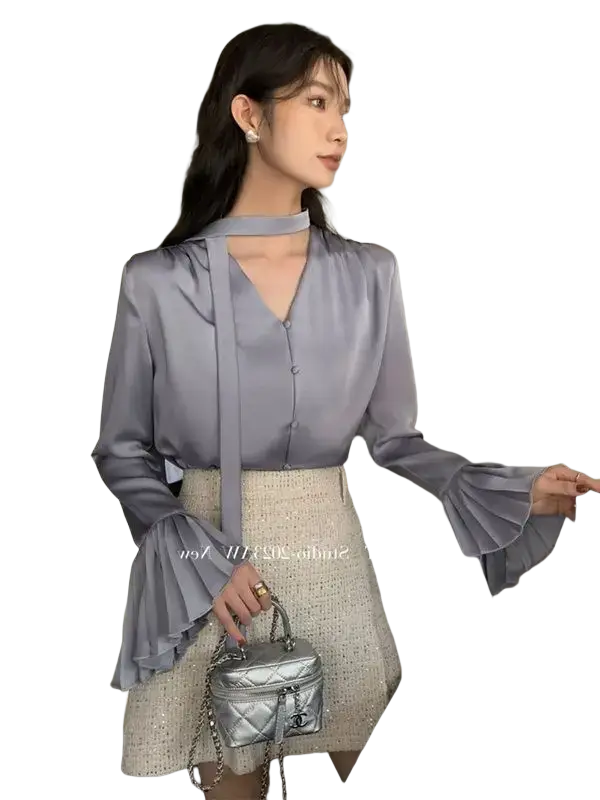 Silver quilted chain-strap handbag with classic chanel logo emblem paired with cream satin long sleeve pleated blouse