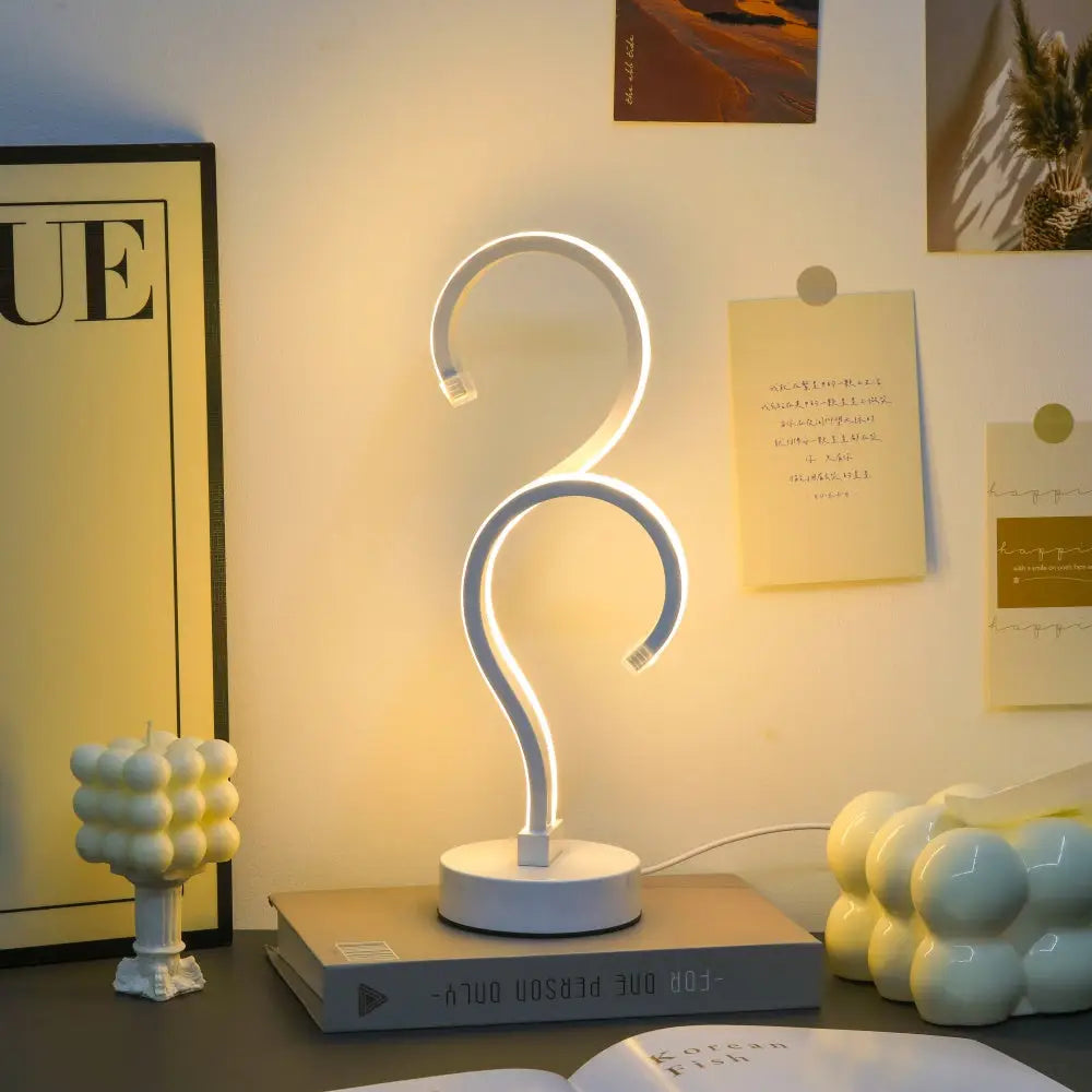 A sleek white modern question mark LED desk lamp with curved s-shaped design and circular base with 3 color modes