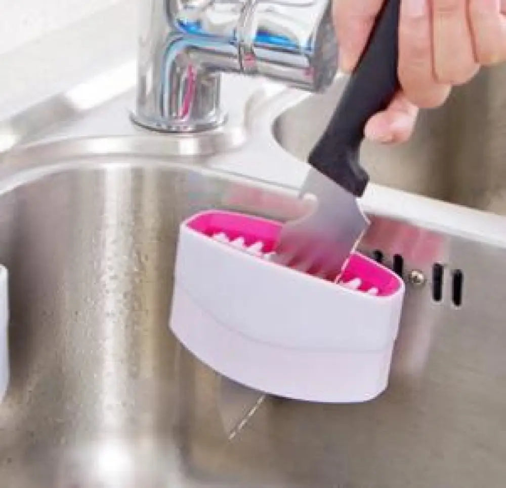 Multiuse suction cup kitchen brush and utensil scrubber with pink and white plastic toothed knife sharpener