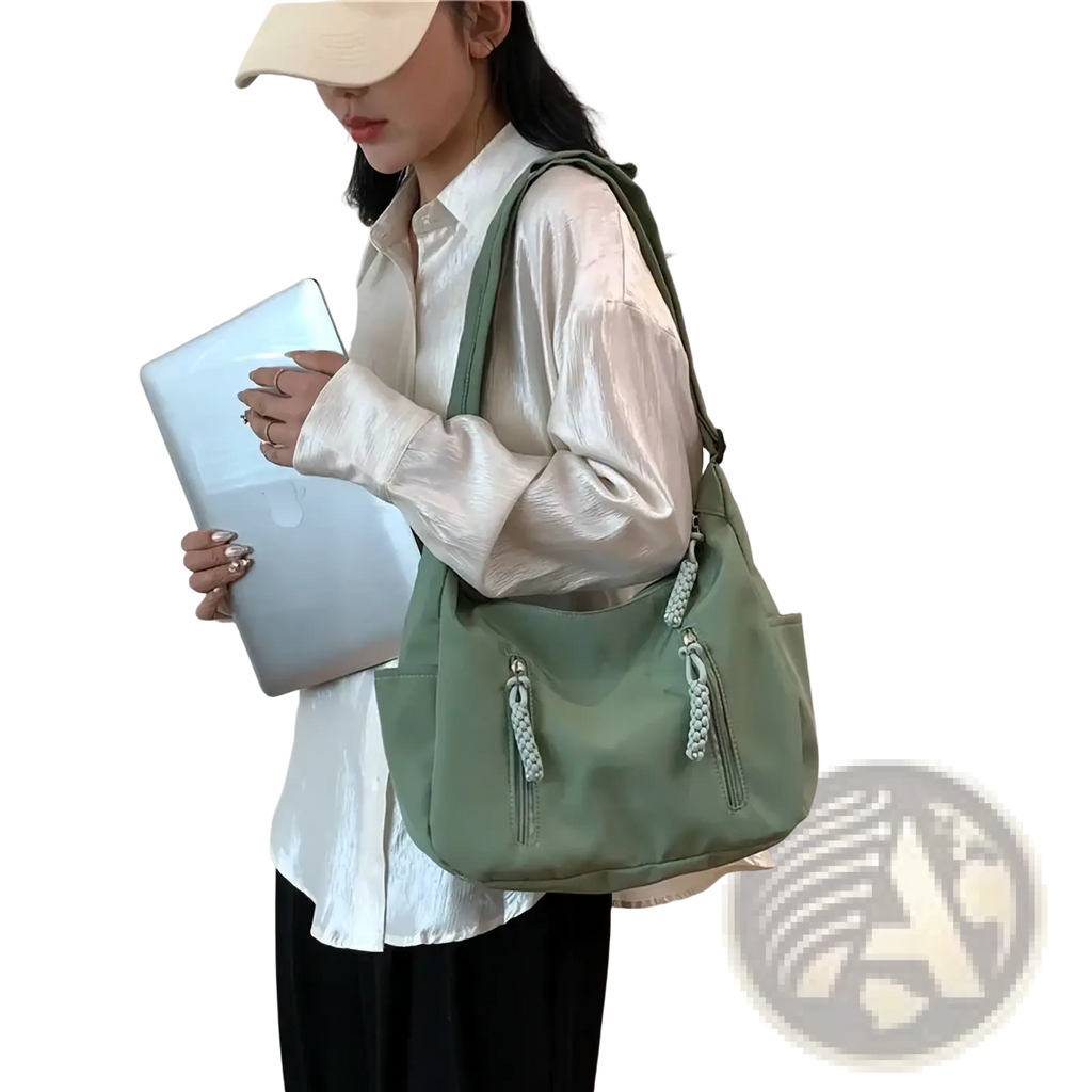 A sage green crescent nylon crossbody bag with braided zipper pulls and one adjustable shoulder strap