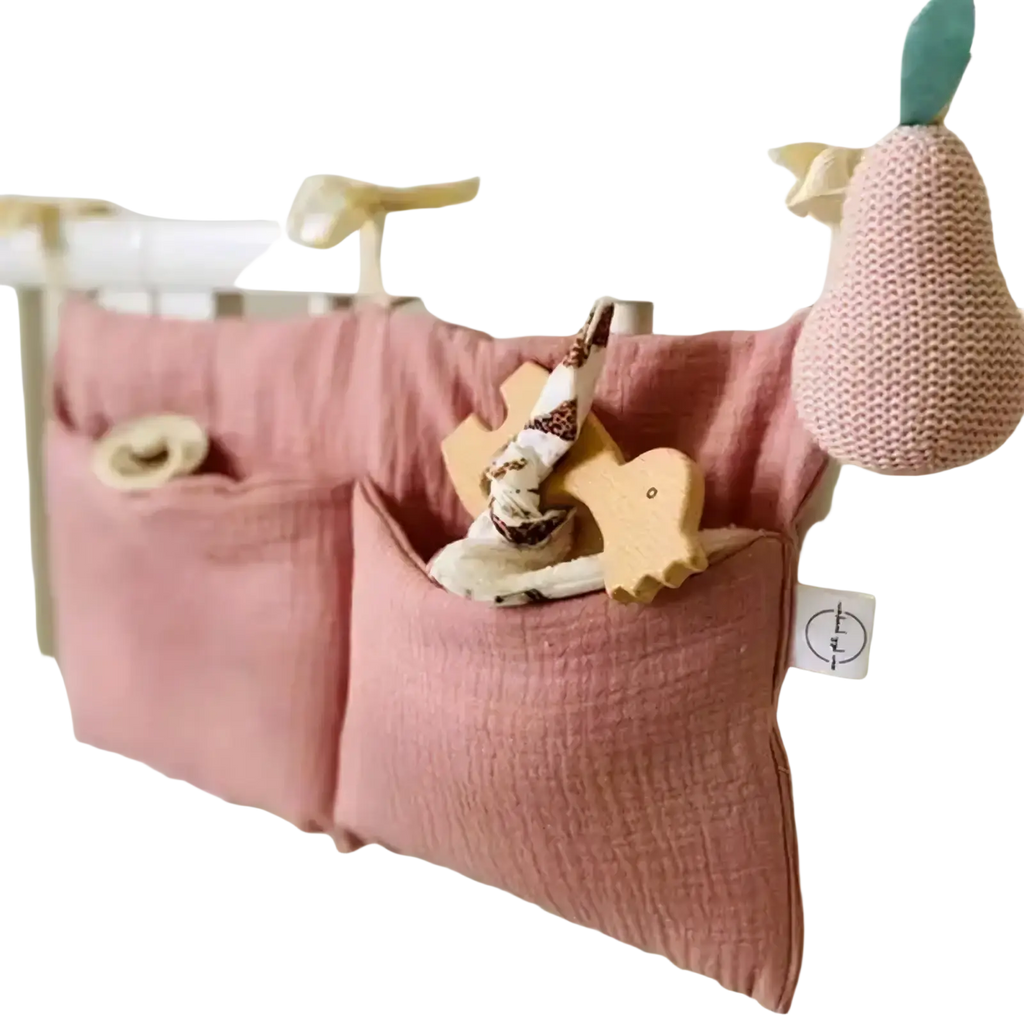 Pink cotton crib storage bag diaper organizer with two pockets hanging on crib rail for convenient storage