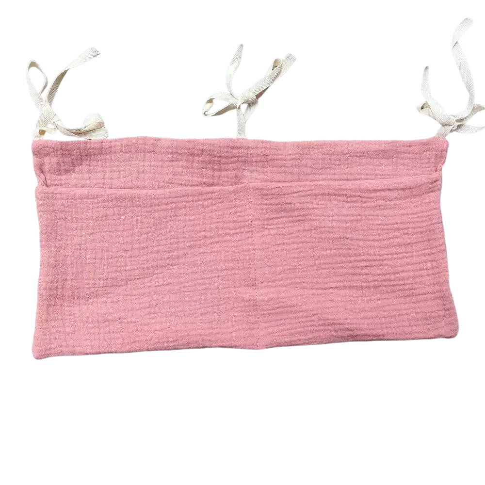 Soft pink textured cotton bandeau top with adjustable white fabric shoulder ties shown with crib storage bag diaper organizer