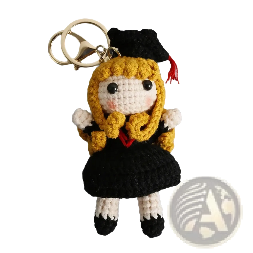 Crochet graduation doll keychain featuring golden yarn hair, black cap and gown, and white face with rosy cheeks