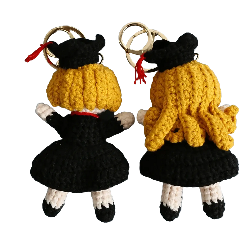 Crochet graduation doll keychains with golden yellow yarn hair black caps and gowns white socks and silver metal rings