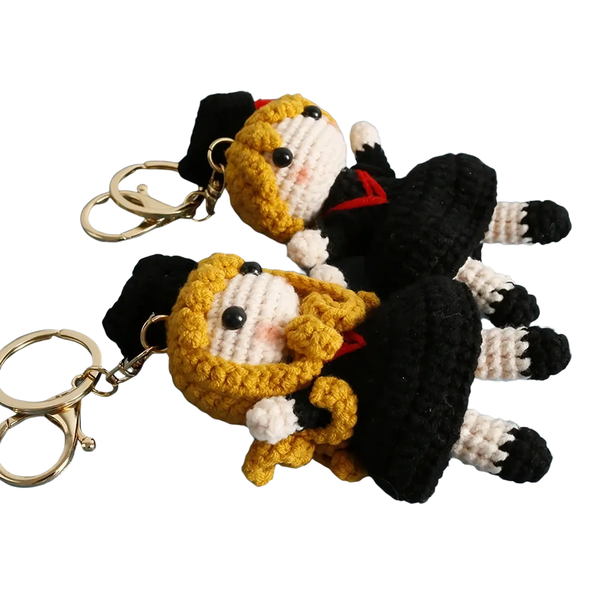 Crochet graduation doll keychain featuring two identical figures with golden hair black and white outfits and red accents