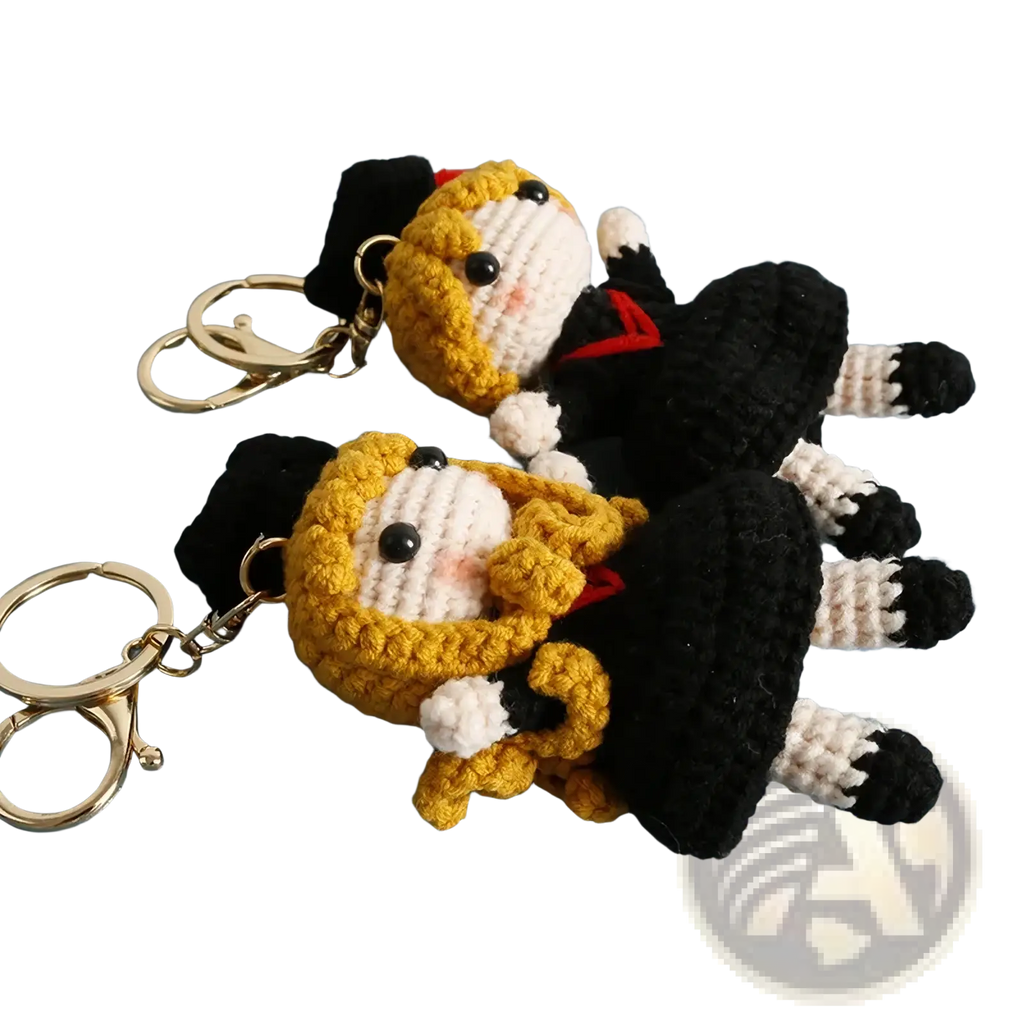 Crochet graduation doll keychain featuring two identical figures with golden hair black and white outfits and red accents