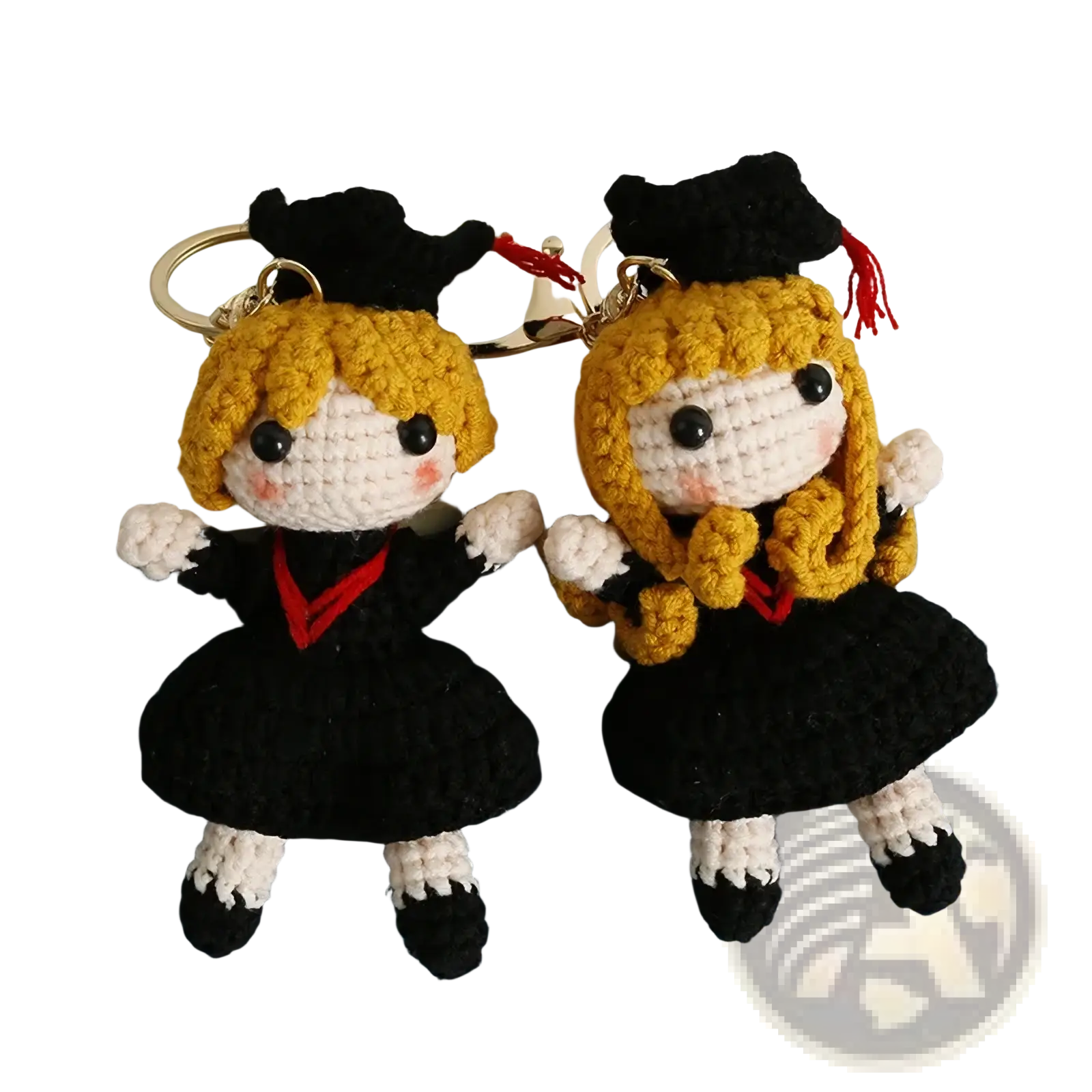 Two crocheted graduation doll keychains featuring blonde figures in black caps gowns with red accents white gloves and shoes