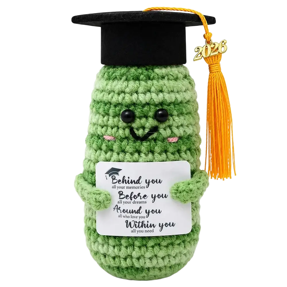 Green crocheted cactus figurine wearing a black graduation cap with orange tassel holding a white card for graduation keepsake