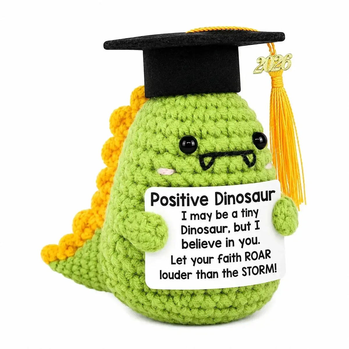 A green crocheted dinosaur with a black graduation cap holding a positive dinosaur sign in a crochet graduation puppy pocket hug keepsake