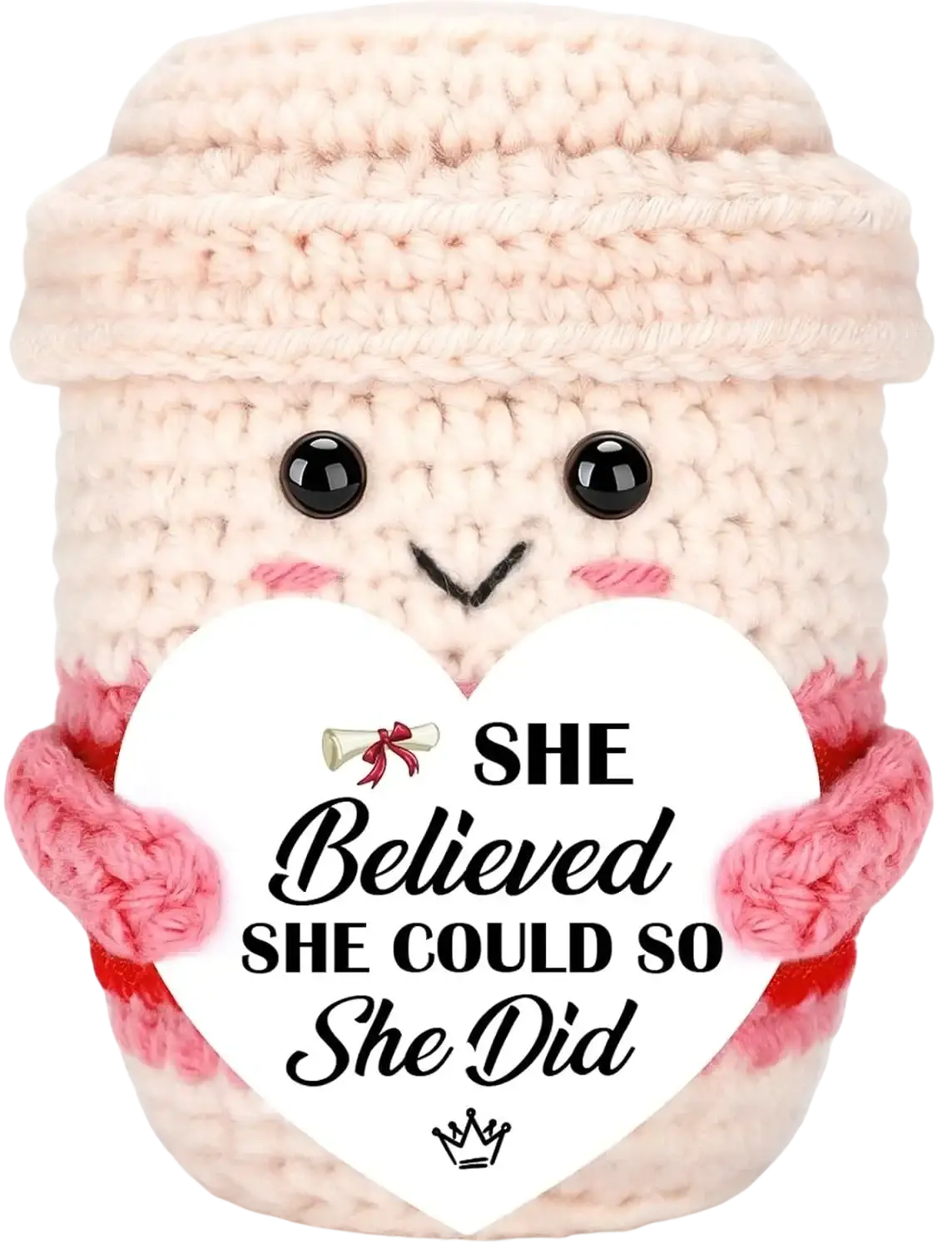 A cream-colored crocheted coffee cup plush puppy with black eyes holding a white heart sign for graduation keepsake