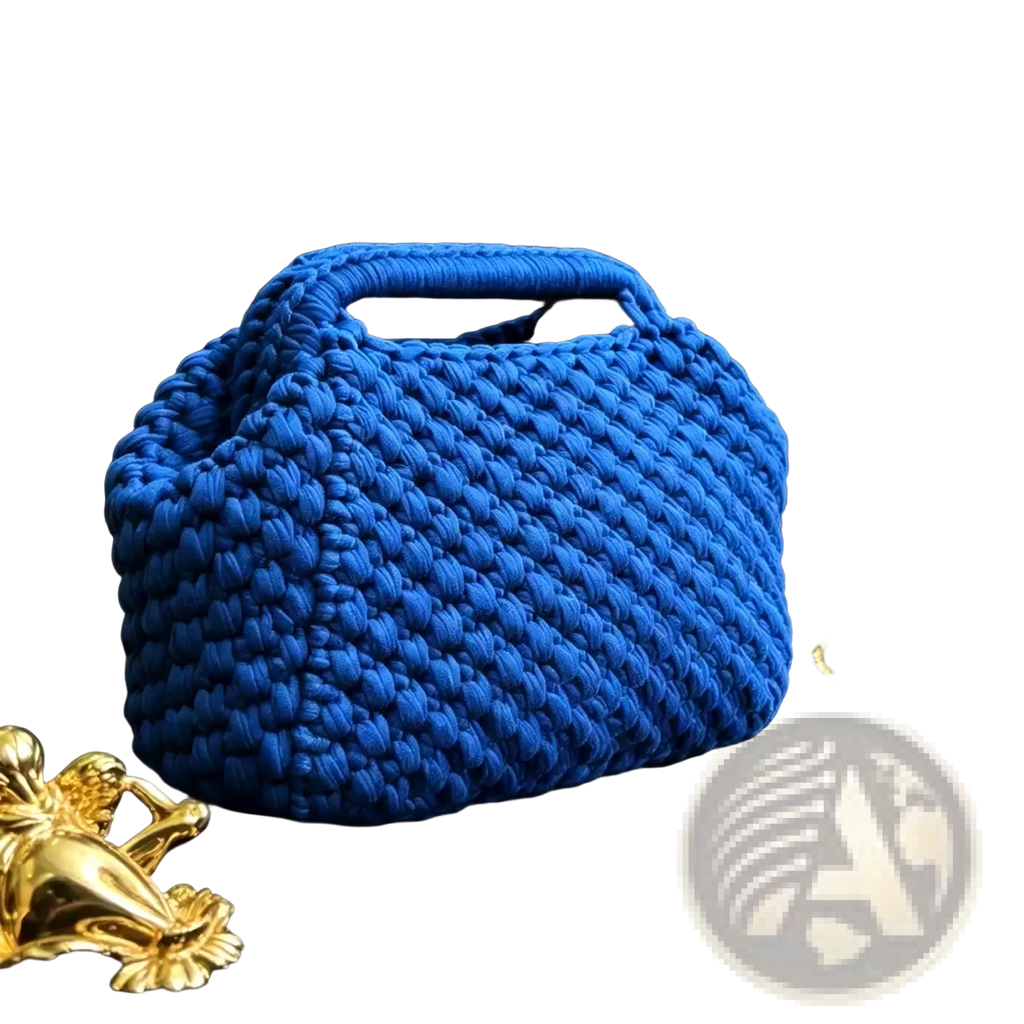 A vibrant cobalt blue crocheted knit shoulder bag with chunky texture and integrated top handle woven tote purse