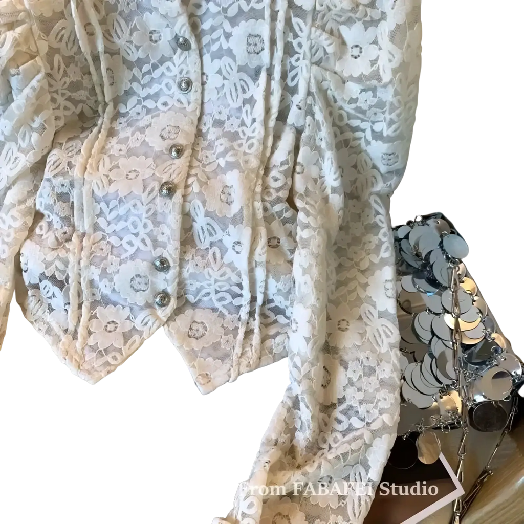 A delicate ivory crocheted lace bubble sleeve blouse featuring floral patterns and silver-toned buttons