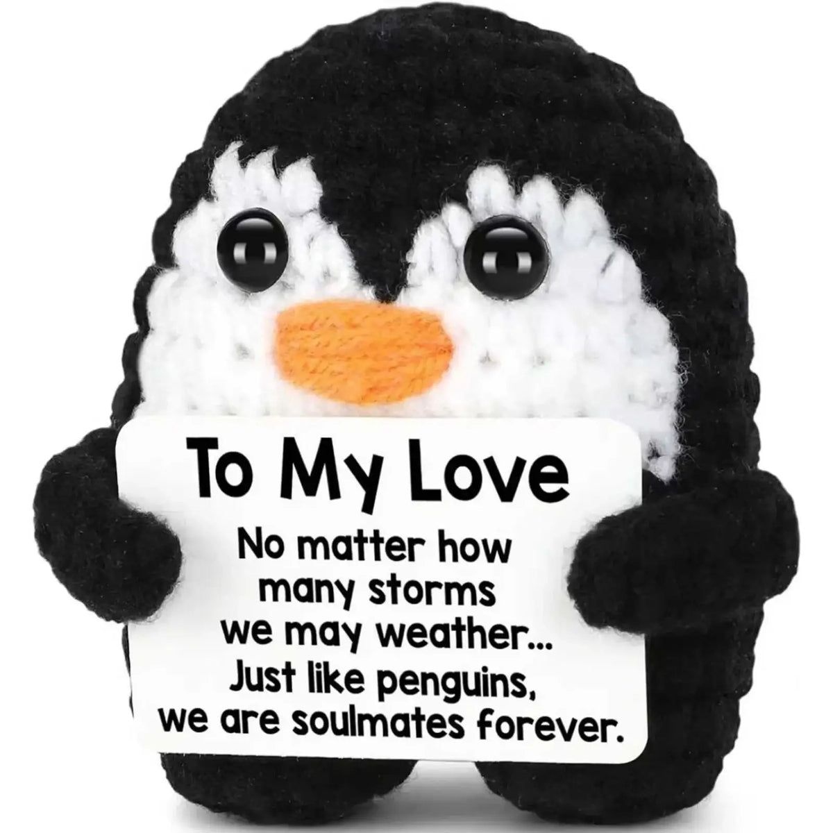 A black and white crocheted penguin plush toy with an orange beak holding a card to my love for gifting