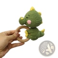 Crocheted unicorn baby comforter security blanket featuring a green crocheted dinosaur rattle with yellow spikes and pink nose attached to a wooden ring
