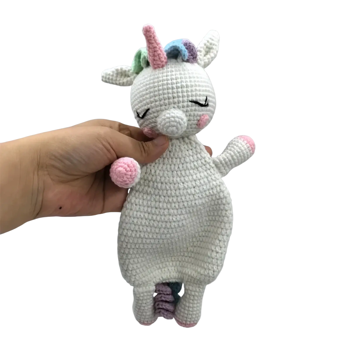 A soft crocheted unicorn baby comforter security blanket with white body pink hooves nose and pastel rainbow horn