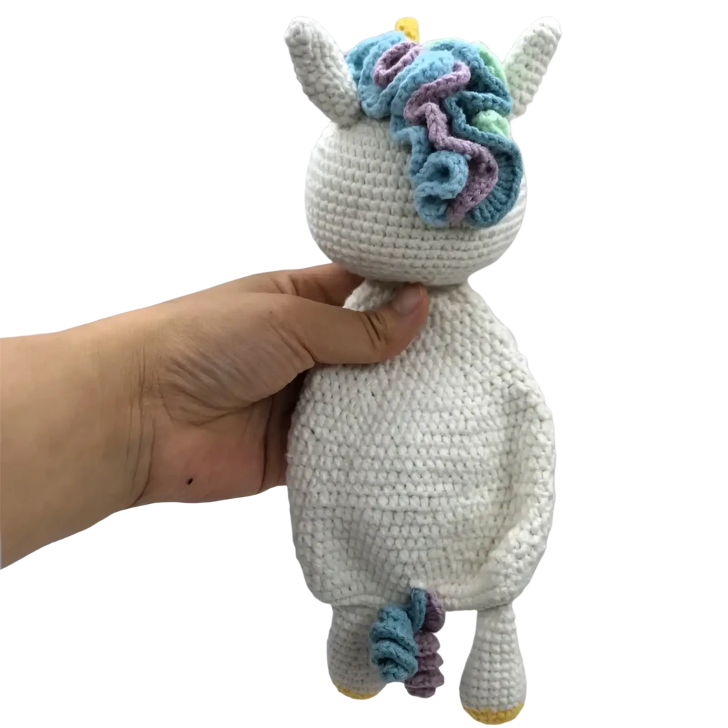 A soft white crocheted unicorn baby comforter with colorful blue and purple yarn mane yellow horn and hooves