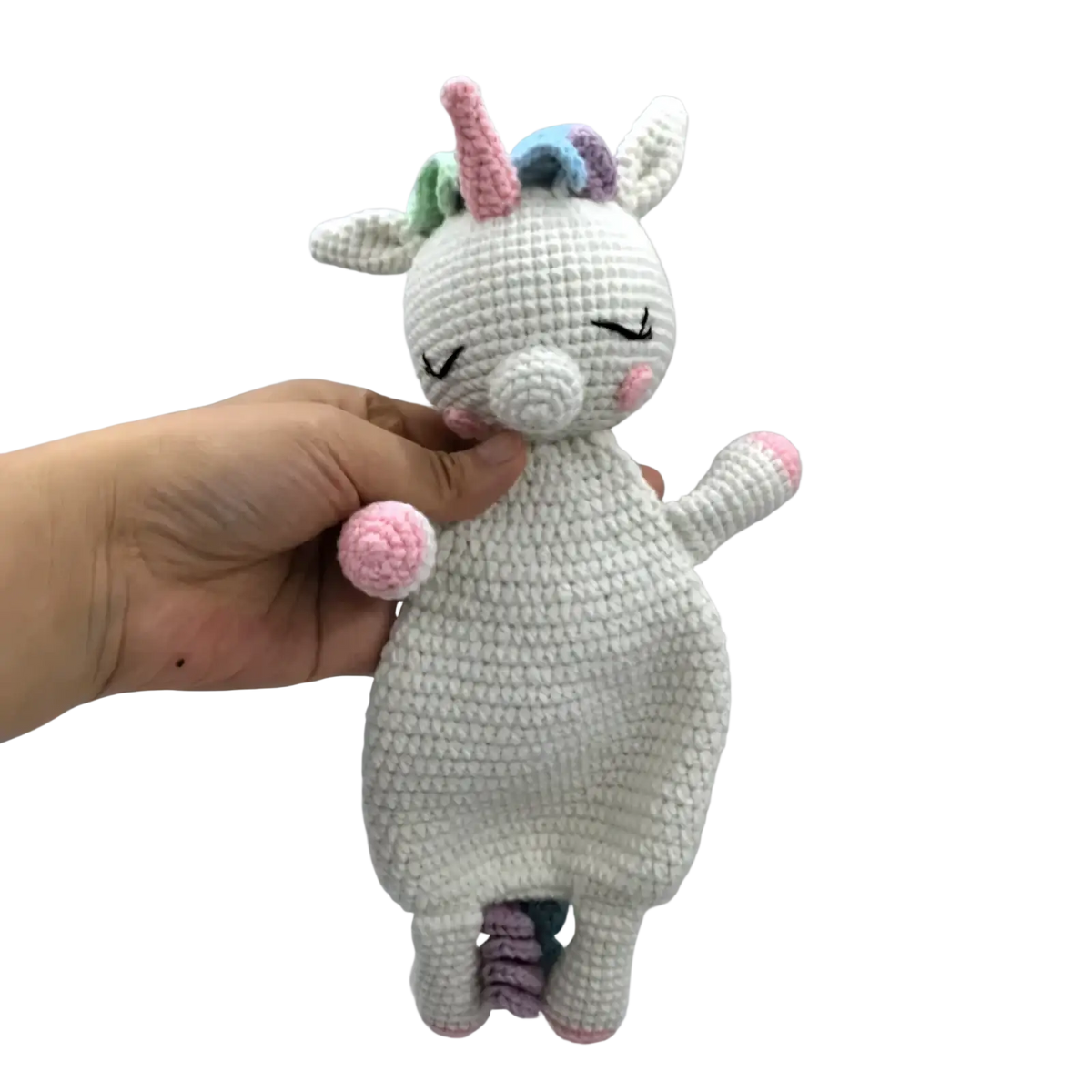 A soft white crocheted unicorn baby comforter security blanket with pink accents and a colorful rainbow mane