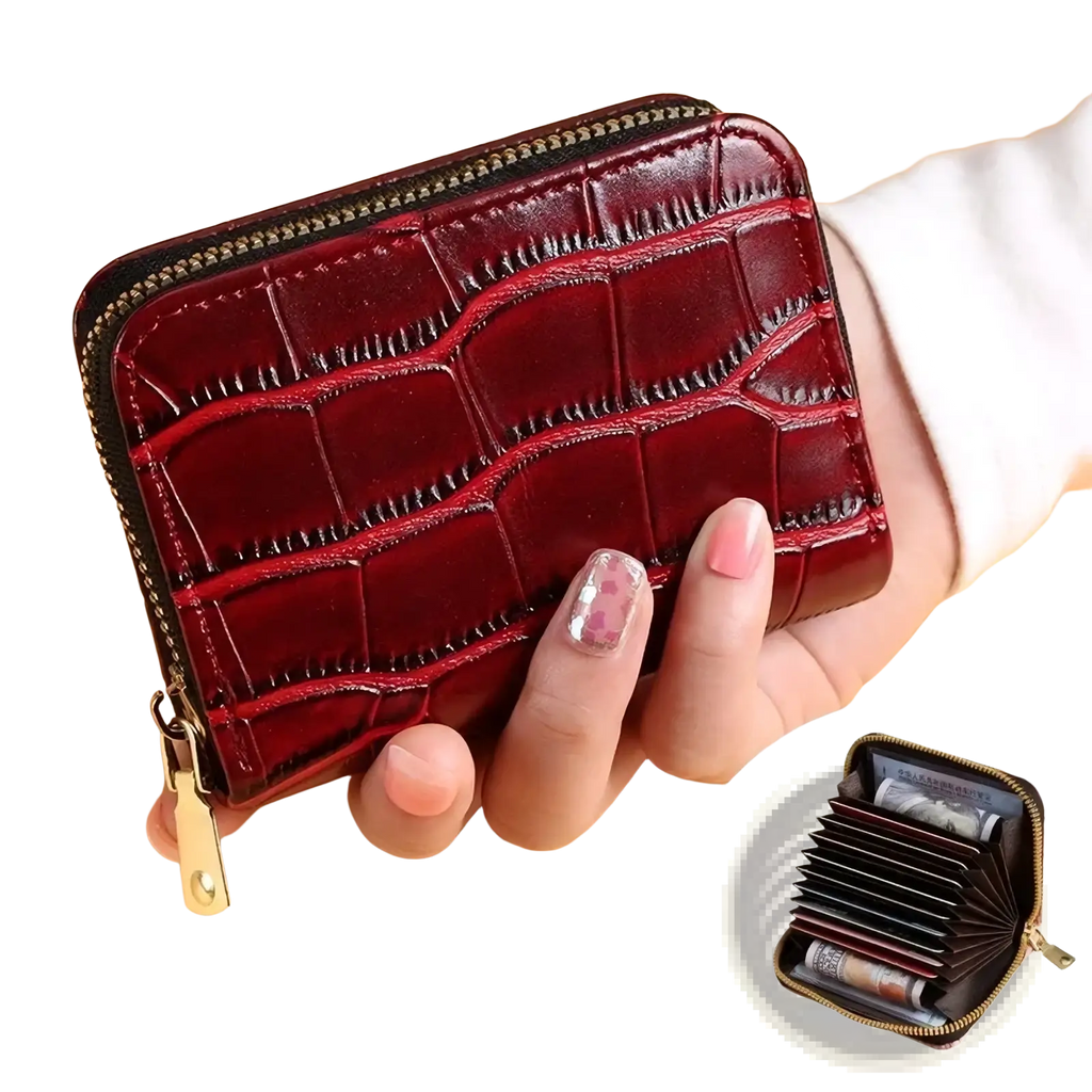 A glossy burgundy crocodile leather accordion card holder wallet with a gold zipper and pull tab