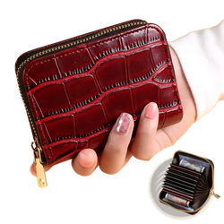 A glossy burgundy crocodile leather accordion card holder wallet with a gold zipper and pull tab