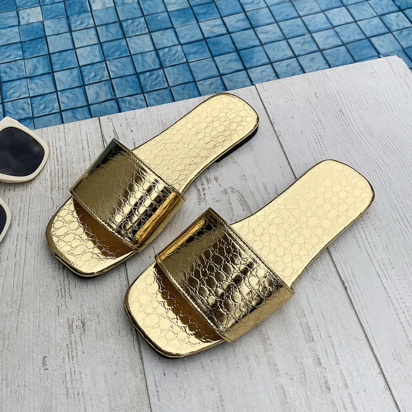 Gold-colored slide sandals with shiny crocodile-skin texture and square toe for flat beach wear