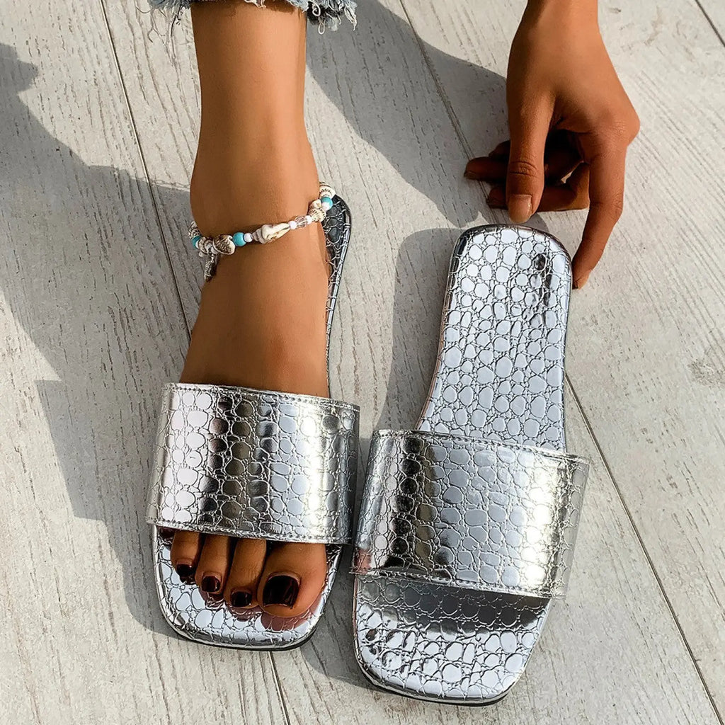 Silver crocodile-textured square toe flat slide sandals with shiny metallic finish ideal for beachwear