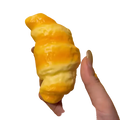 A golden-brown glossy croissant squeeze toy stress relief bread held in hand as a croissant squeeze toy