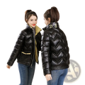 Black cropped quilted puffer jacket with a shiny glossy finish and gold trim on collar and waistband