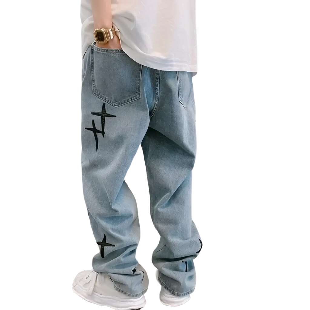 Light-wash denim baggy wide leg jeans with black embroidered cross designs on the outer thigh and lower leg