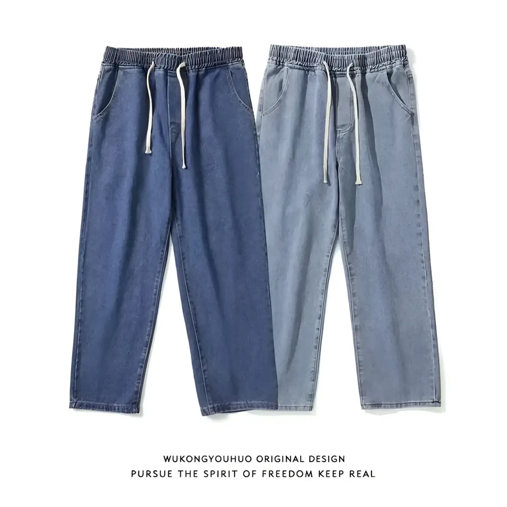 A pair of cross embroidered baggy wide leg denim jeans in deep indigo and light gray with white drawstrings