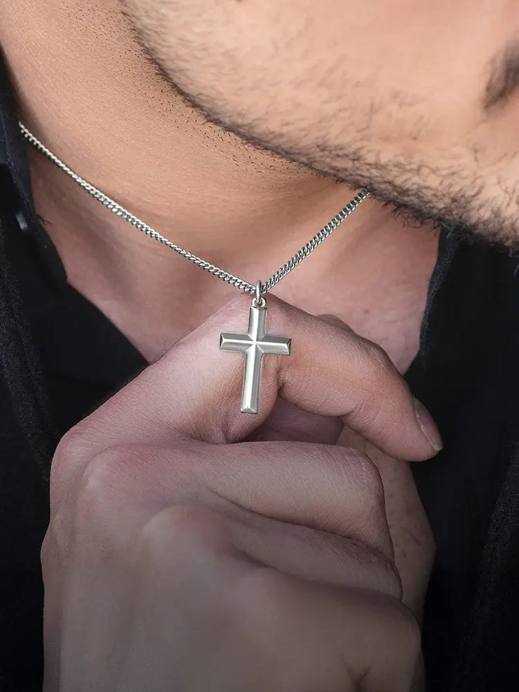 Geometric silver cross pendant on a stainless steel curb chain showcasing a modern religious jewelry design