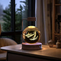 A glowing 3d crystal ball dinosaur night light usb bedside lamp with etched fairy design on a metallic stand
