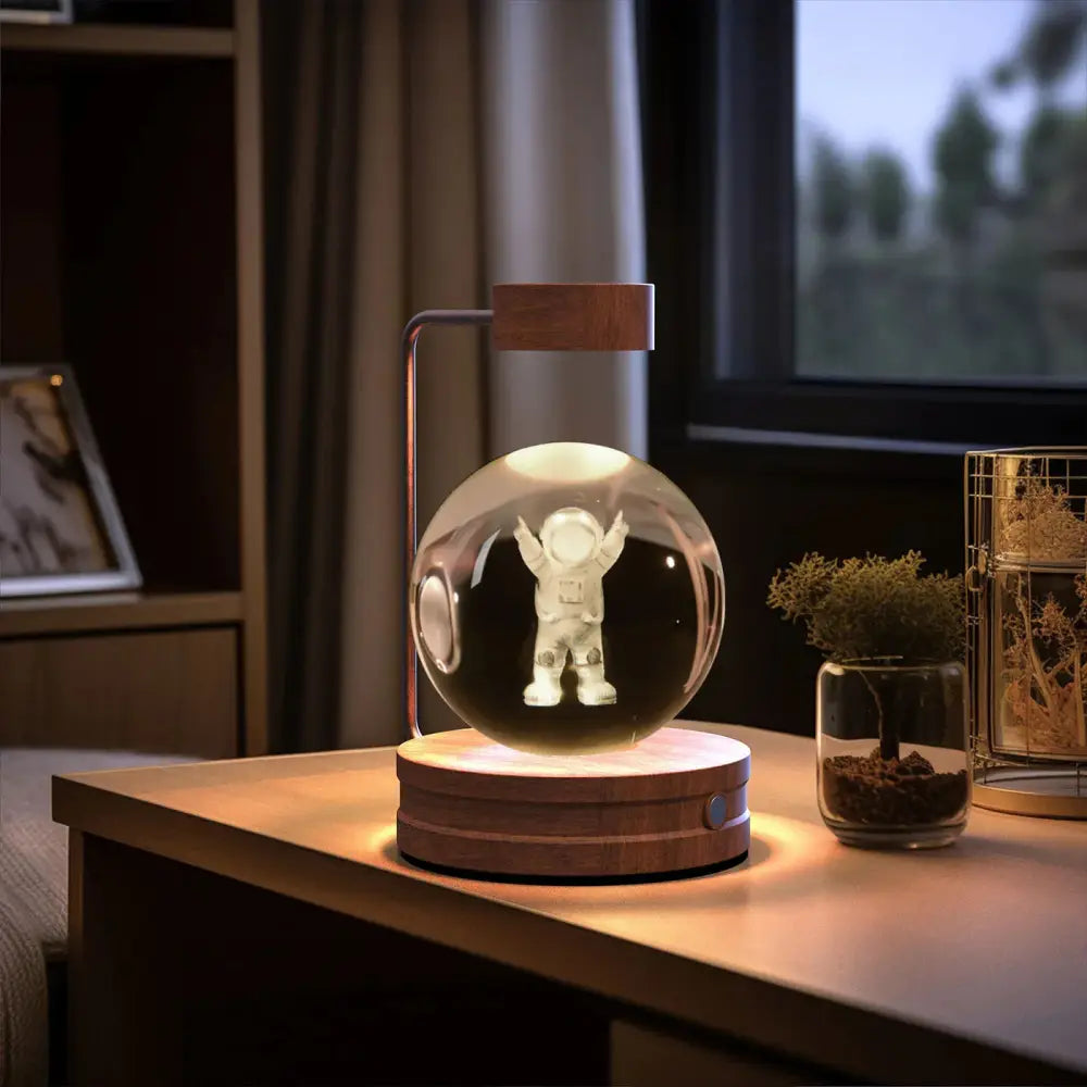 A glowing transparent spherical usb night lamp with a white astronaut figurine and wooden base and top