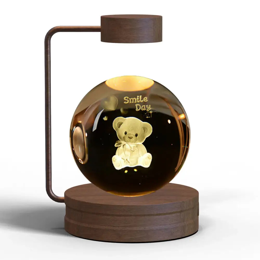 A warm-glowing transparent glass 3d crystal ball dinosaur night light with floating teddy bear and smile day inscription