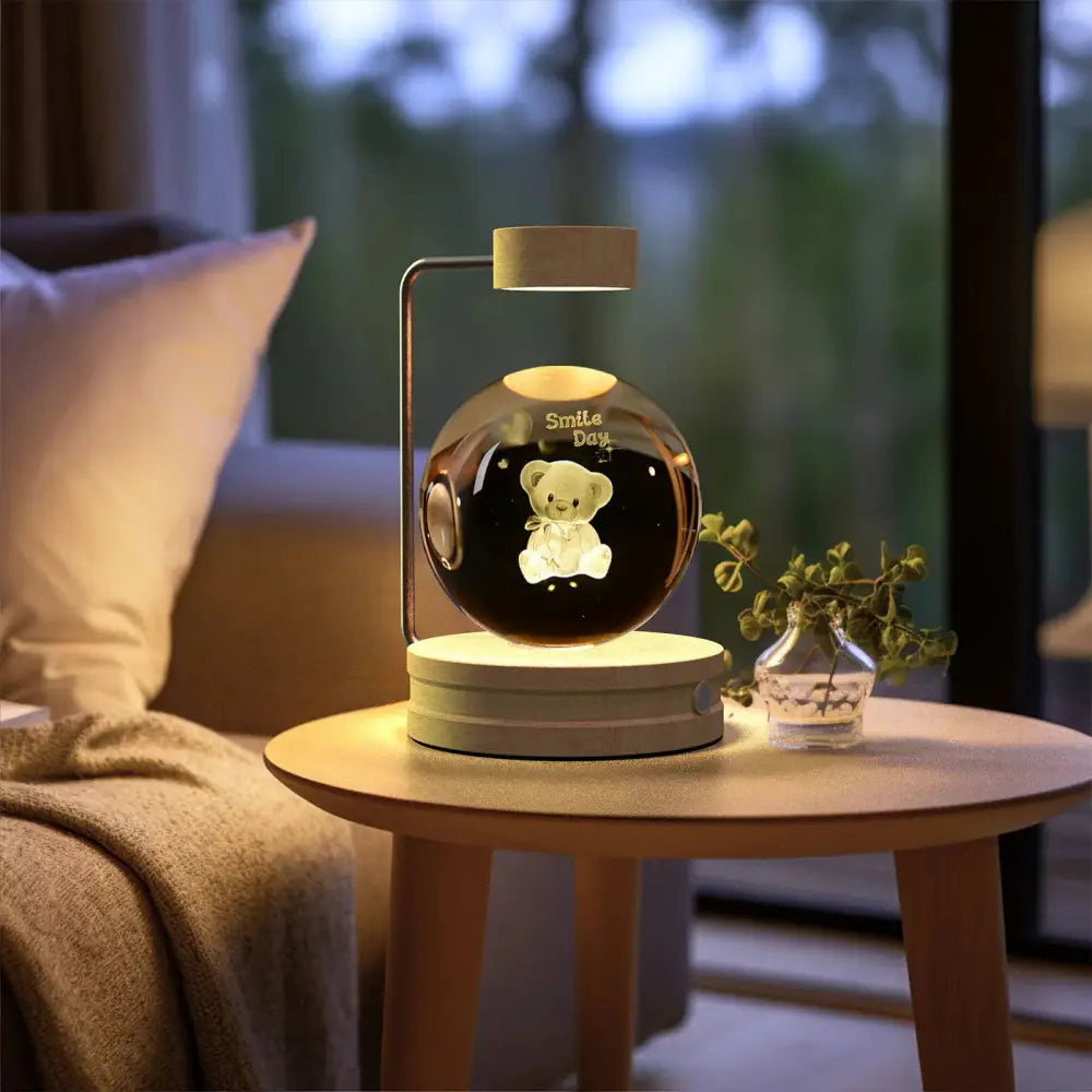 A sleek glossy black spherical 3d crystal ball dinosaur night light with an illuminated white teddy bear design inside
