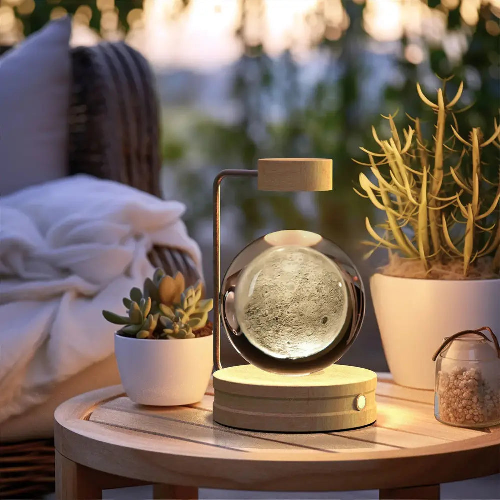 Floating spherical moon lamp with illuminated lunar surface inside glass globe levitating above wooden base bedside lamp