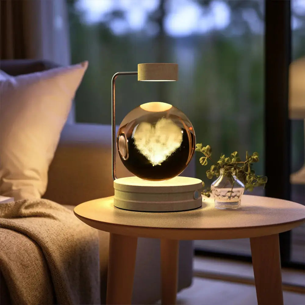 A sleek floating spherical usb crystal ball lamp with reflective metallic finish and illuminated heart design inside