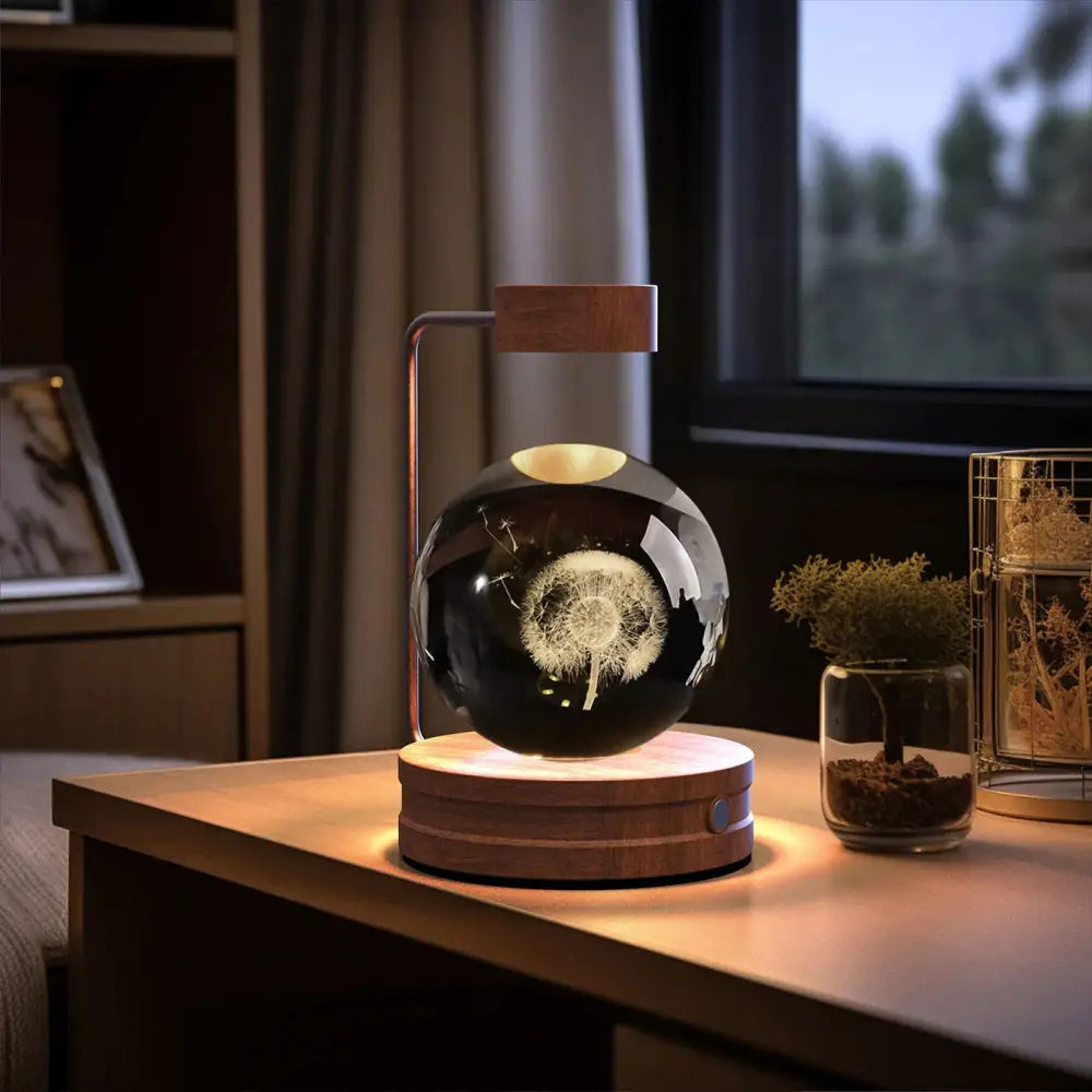 Floating black glass orb with white dandelion etching suspended by magnetic levitation on wooden base and cap bedside lamp
