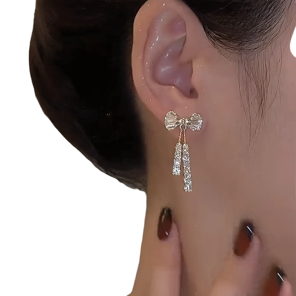 Gold-toned crystal bow and pearl dangle earrings featuring sparkling crystals and elegant dangling strands