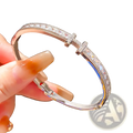 A sleek silver crystal cross cuff bracelet featuring princess cut crystals and two cross-shaped charms with clear stones
